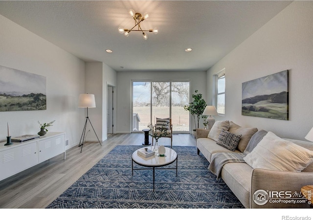 living room featuring wood-type flooring, a healthy amount of sunlight, a notable chandelier, and a textured ceiling