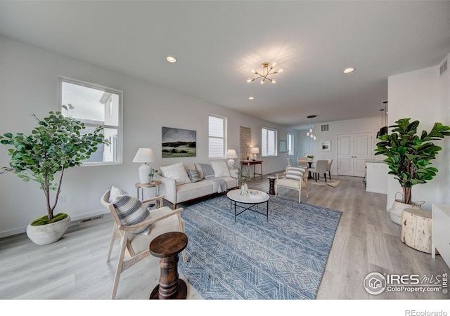 living room with light wood-type flooring and a notable chandelier