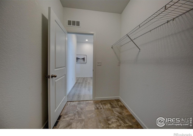 walk in closet with light hardwood / wood-style floors