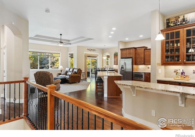 kitchen with hanging light fixtures, a breakfast bar area, stainless steel fridge, and light stone counters