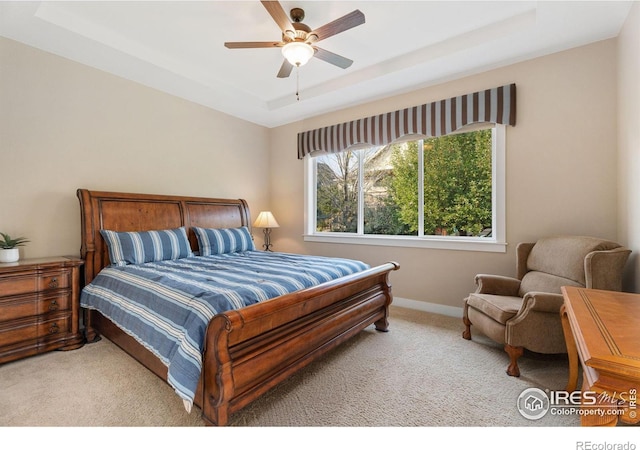 carpeted bedroom featuring a raised ceiling and ceiling fan