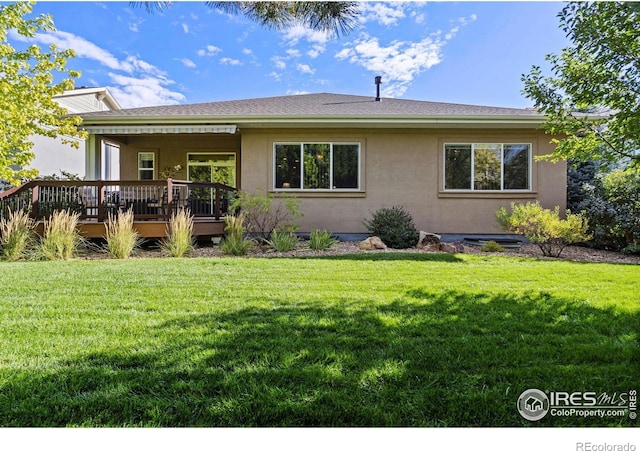 back of property featuring a wooden deck and a lawn