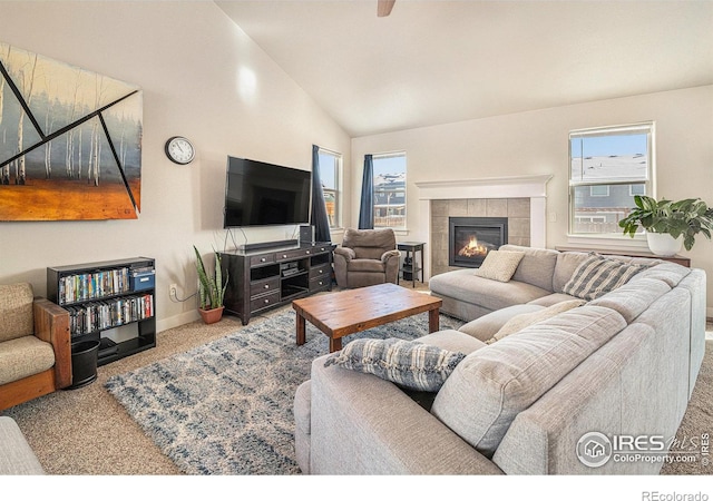 carpeted living room featuring a tile fireplace, lofted ceiling, and a healthy amount of sunlight