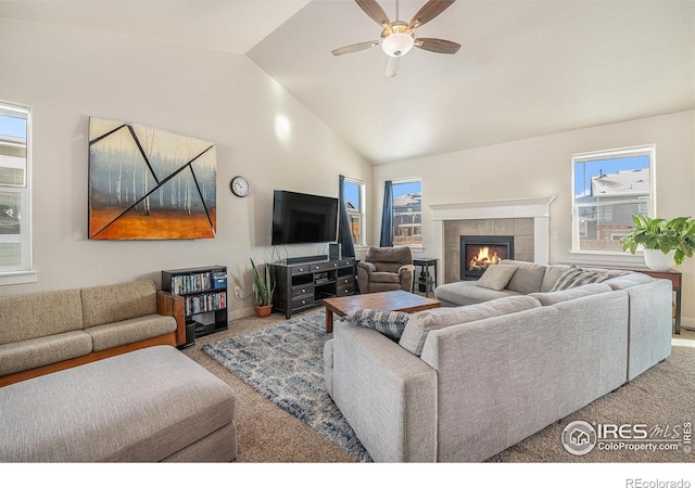 carpeted living room featuring a tiled fireplace, vaulted ceiling, and ceiling fan