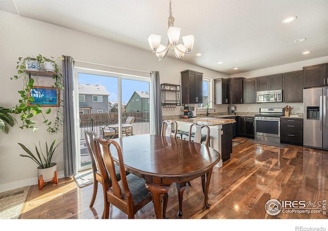 dining room featuring dark wood-type flooring, sink, and a notable chandelier