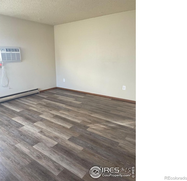 spare room featuring a baseboard radiator, dark hardwood / wood-style floors, a wall unit AC, and a textured ceiling