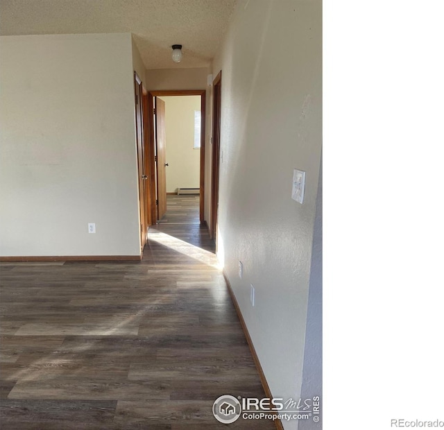 hall with dark wood-type flooring, a textured ceiling, and a baseboard heating unit