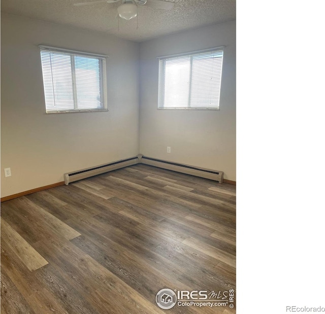 empty room featuring ceiling fan, a healthy amount of sunlight, dark hardwood / wood-style flooring, and a textured ceiling