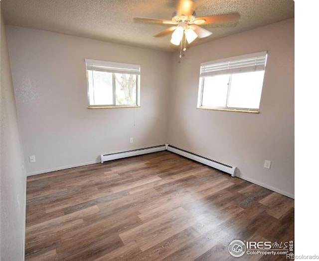 spare room with hardwood / wood-style flooring, ceiling fan, baseboard heating, and a textured ceiling