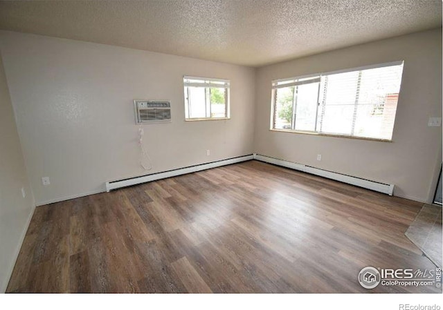 empty room with hardwood / wood-style flooring, a baseboard heating unit, a wall mounted air conditioner, and a textured ceiling