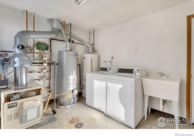 washroom with sink, gas water heater, and washing machine and dryer