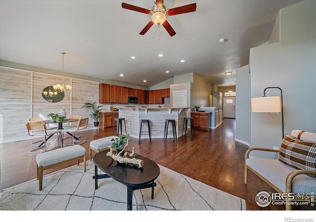 living room with lofted ceiling, wooden walls, ceiling fan with notable chandelier, and light wood-type flooring