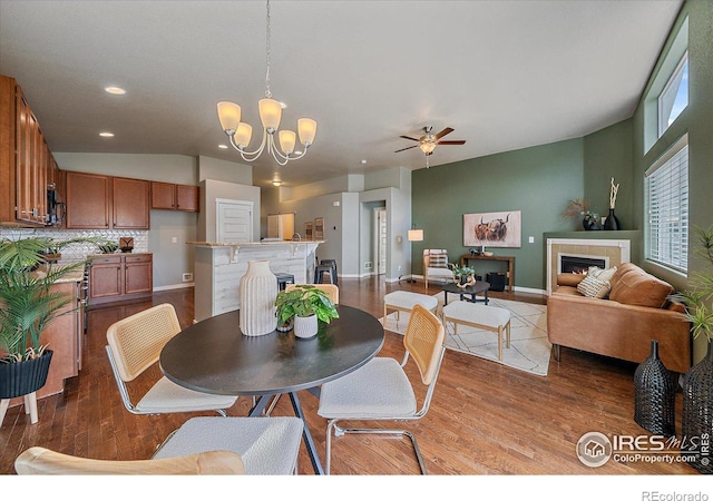 dining room with lofted ceiling, ceiling fan with notable chandelier, and wood-type flooring