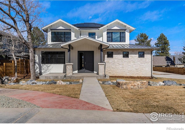 view of front of house featuring a garage, a porch, a front yard, and solar panels