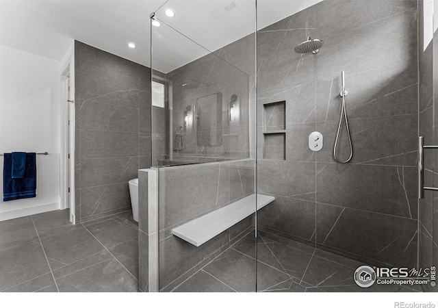 bathroom with a tile shower and toilet