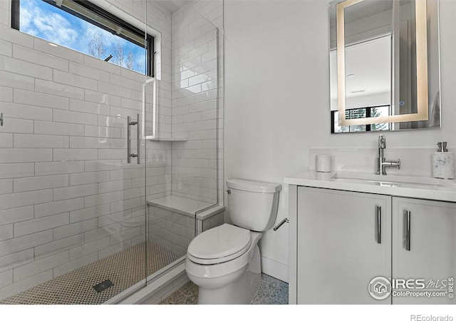 bathroom featuring vanity, a shower with door, and toilet