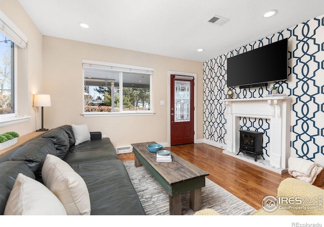 living room with hardwood / wood-style flooring, a healthy amount of sunlight, and a wood stove