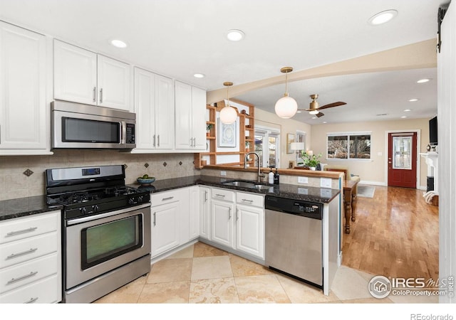 kitchen featuring sink, backsplash, stainless steel appliances, white cabinets, and kitchen peninsula