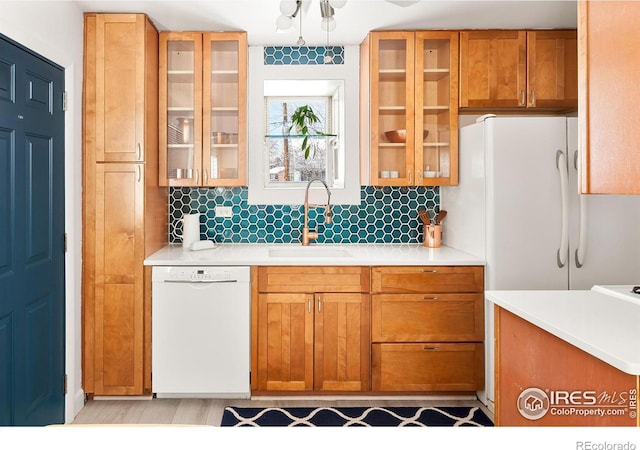 kitchen featuring sink, white appliances, decorative backsplash, and light wood-type flooring