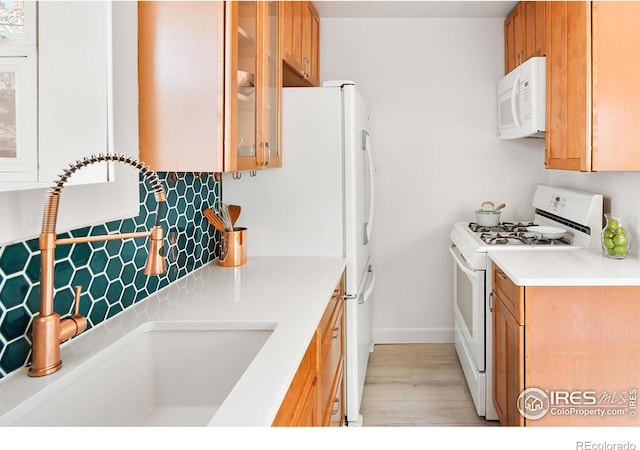 kitchen featuring tasteful backsplash, white appliances, sink, and light wood-type flooring