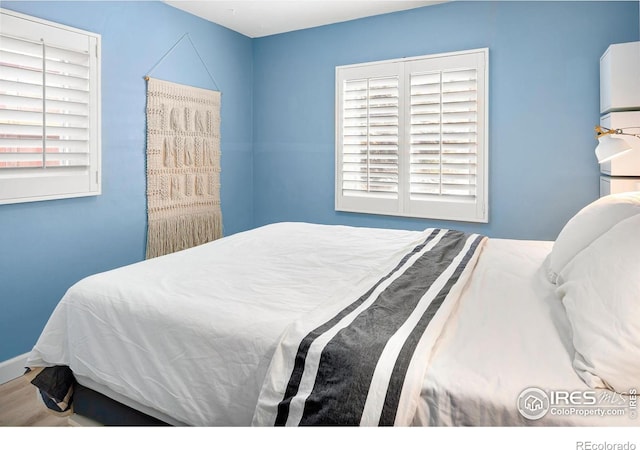 bedroom featuring hardwood / wood-style floors and refrigerator