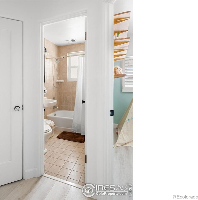 bathroom featuring shower / tub combo with curtain, tile patterned flooring, and toilet