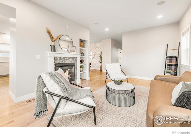 living room with a tiled fireplace and light hardwood / wood-style floors