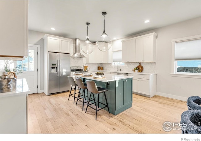 kitchen featuring wall chimney exhaust hood, white cabinetry, and stainless steel appliances