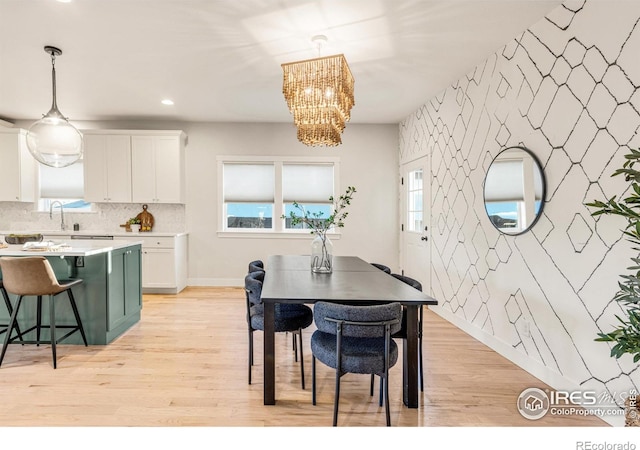 dining room with a chandelier, sink, and light wood-type flooring