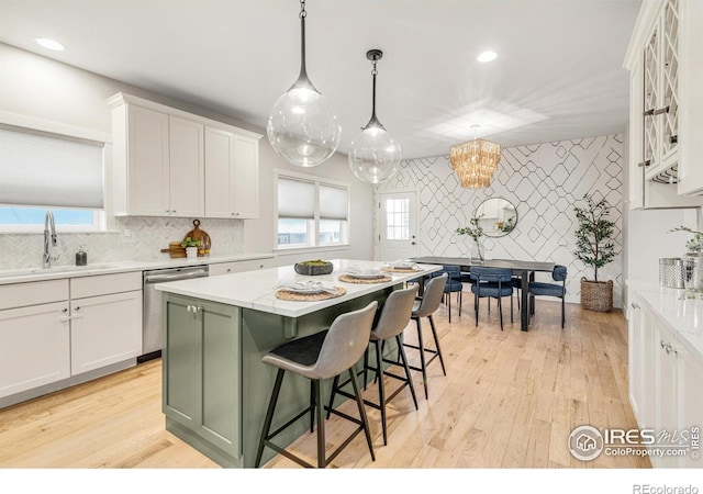 kitchen featuring dishwasher, a center island, sink, and white cabinets