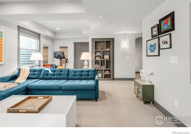 living room with a raised ceiling, light colored carpet, and built in features