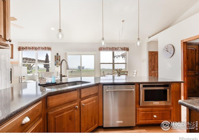 kitchen with hanging light fixtures, appliances with stainless steel finishes, sink, and lofted ceiling