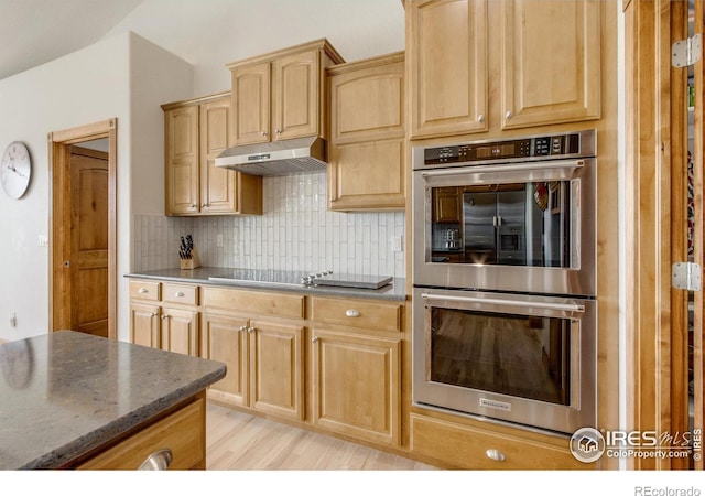 kitchen featuring light wood-type flooring, light brown cabinets, double oven, dark stone counters, and backsplash