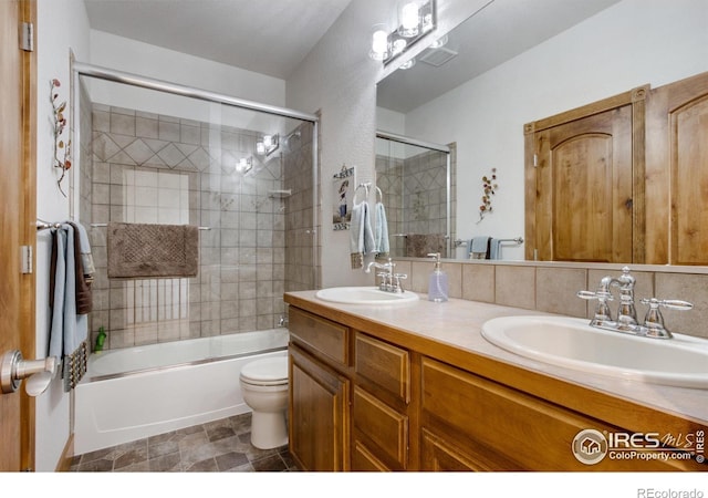 full bathroom featuring enclosed tub / shower combo, vanity, toilet, and decorative backsplash