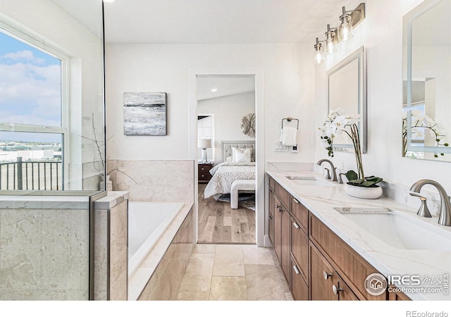 bathroom featuring tiled bath and vanity