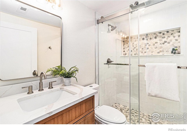 bathroom with vanity, a shower with door, and toilet