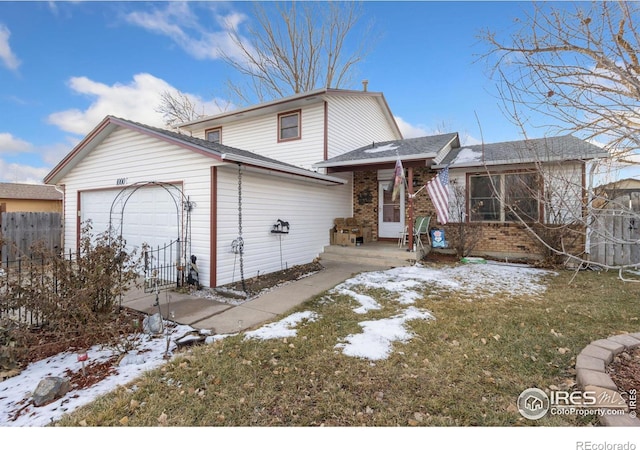 snow covered rear of property featuring a yard and a garage