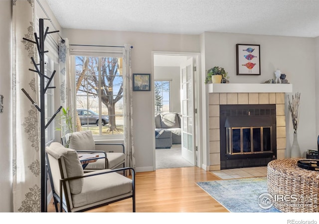 living room with hardwood / wood-style floors, a tile fireplace, and a textured ceiling