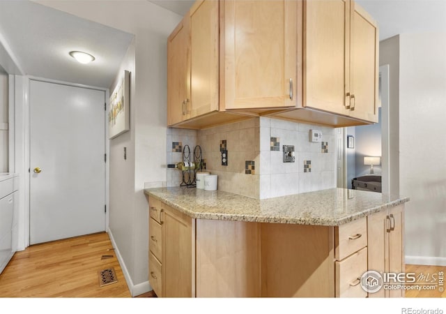 kitchen featuring light stone countertops, light hardwood / wood-style flooring, light brown cabinetry, and decorative backsplash