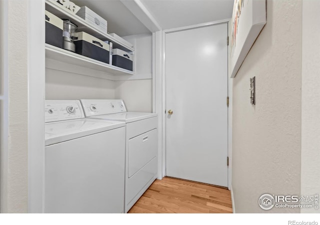 laundry room featuring washing machine and dryer and light hardwood / wood-style flooring