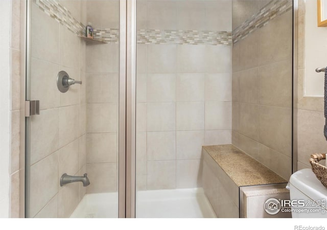 bathroom featuring toilet and a shower with shower door