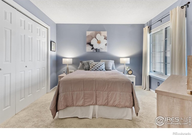 bedroom featuring a closet, light carpet, and a textured ceiling