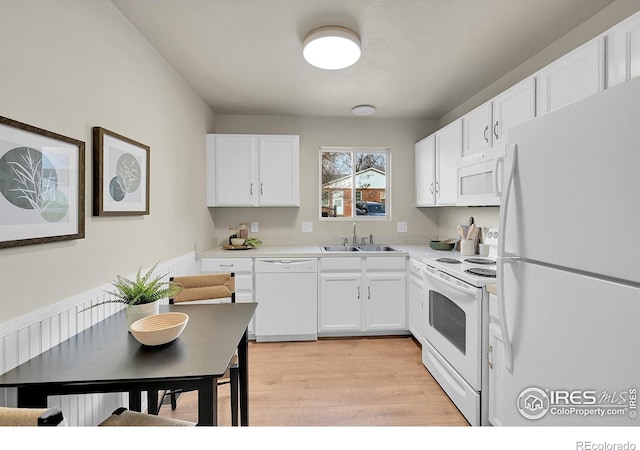 kitchen with white cabinetry, white appliances, sink, and light wood-type flooring