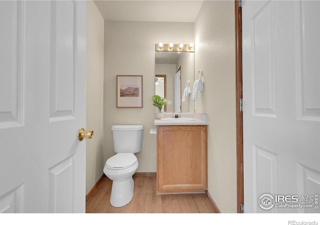 bathroom with wood-type flooring, toilet, and vanity