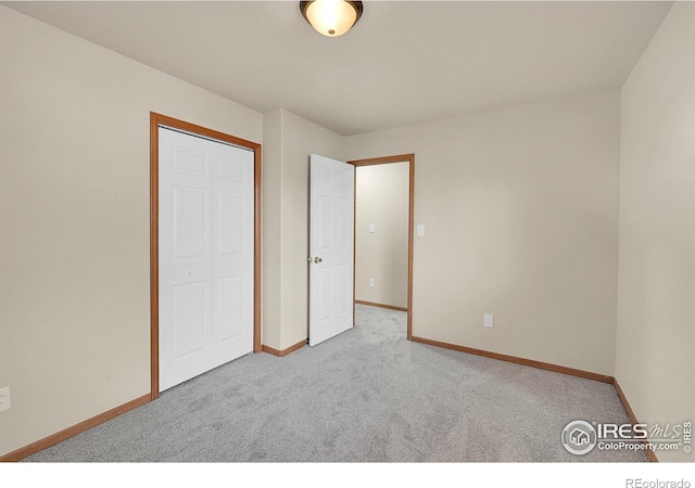 unfurnished bedroom featuring light colored carpet and a closet