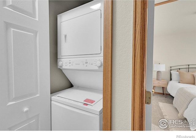 laundry area featuring carpet floors and stacked washer / dryer