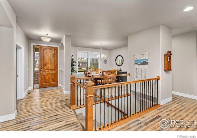 hall with a chandelier and light hardwood / wood-style floors