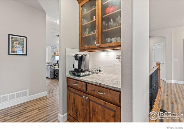 kitchen featuring light stone counters, backsplash, hardwood / wood-style flooring, and ceiling fan