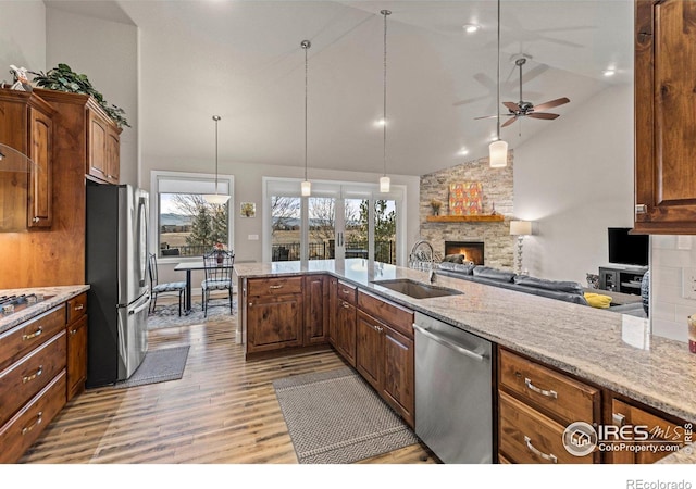 kitchen featuring appliances with stainless steel finishes, sink, a fireplace, and decorative light fixtures