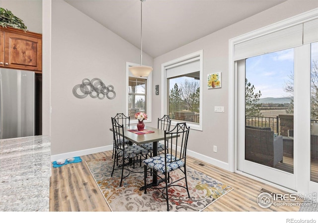 dining space with vaulted ceiling and light hardwood / wood-style flooring